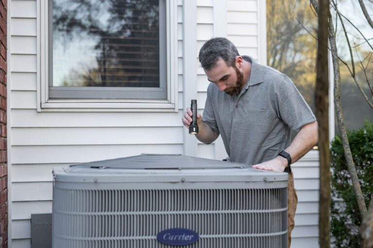 A technician inspects an outdoor HVAC unit for maintenance.
